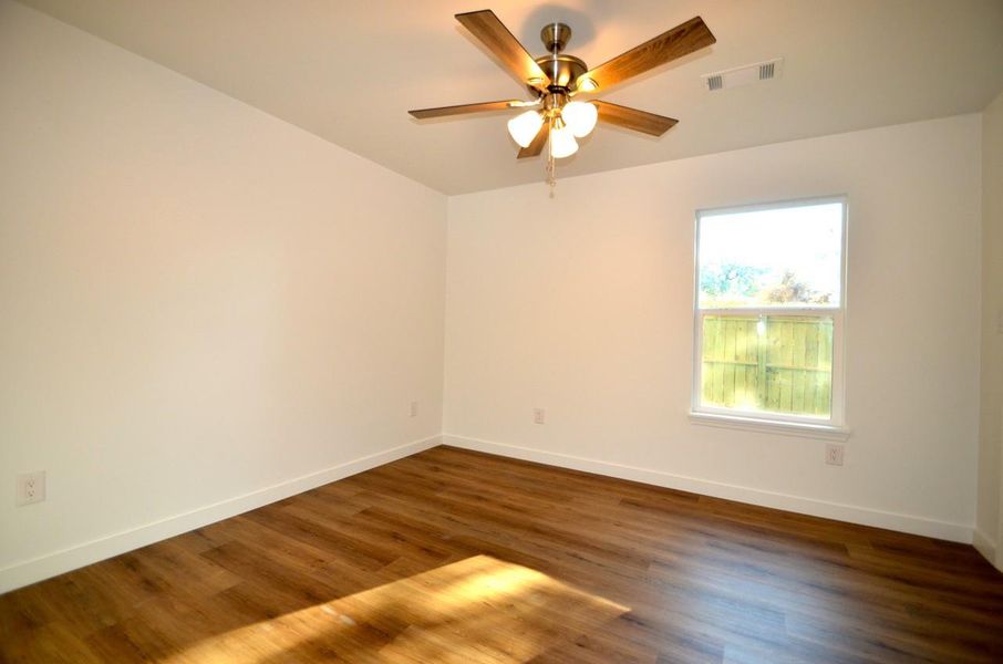 Empty room with dark wood-style floors and a ceiling fan