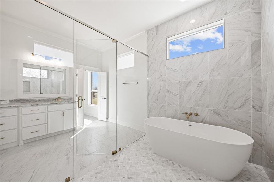 Full bath with a freestanding tub, vanity, tile walls, light marble finish flooring, and a stall shower