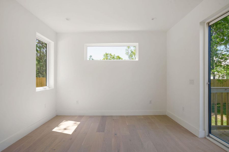 Spare room with baseboards, light wood-type flooring, and a healthy amount of sunlight