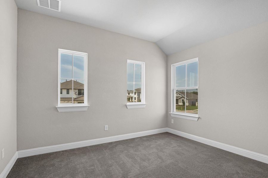 Carpeted empty room featuring lofted ceiling, visible vents, and baseboards Carpeted empty room featuring lofted ceiling, visible vents, and baseboards