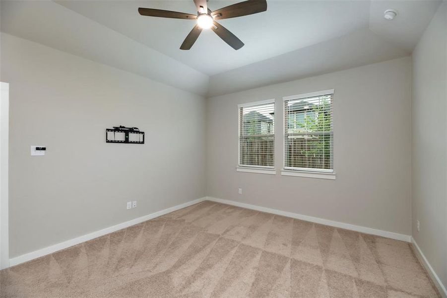 Empty room with lofted ceiling, light carpet, and a ceiling fan Empty room with lofted ceiling, light carpet, and a ceiling fan