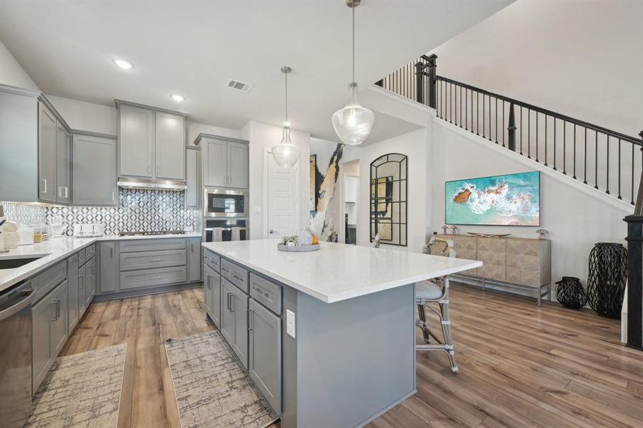 Kitchen featuring hardwood / wood-style floors, a center island, gray cabinetry, and pendant lighting