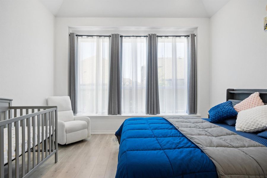 Bedroom with wood finished floors, a crib, and lofted ceiling Bedroom with wood finished floors, a crib, and lofted ceiling