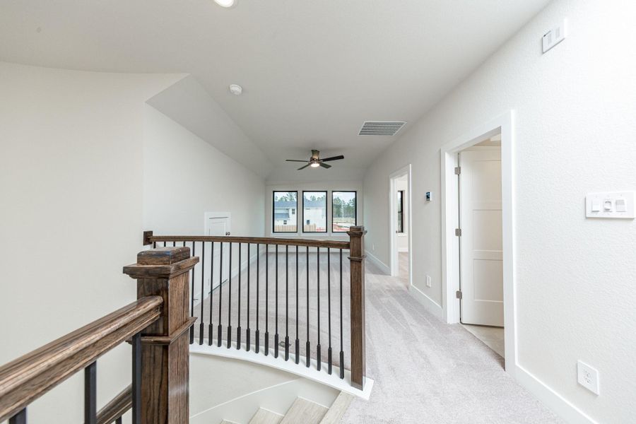 Second floor hallway showcasing the gorgeous stair railing and views of the Game Room and entrance doors to secondary bedrooom and bathroom.