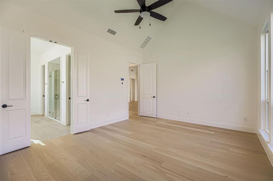 Unfurnished bedroom featuring light wood-type flooring, ceiling fan, and high vaulted ceiling Unfurnished bedroom featuring light wood-type flooring, ceiling fan, and high vaulted ceiling