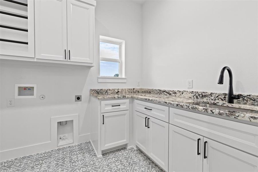 Washroom featuring hookup for a washing machine, sink, cabinets, electric dryer hookup, and light tile patterned floors