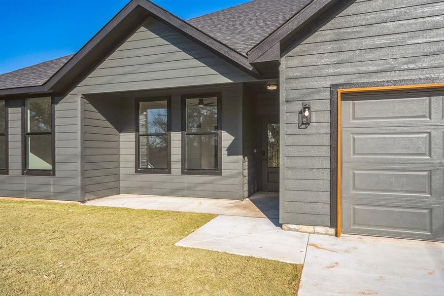 Doorway to property featuring a lawn and a garage