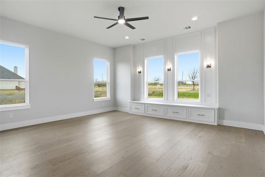 Elegant primary suite showcasing large windows, built-in window seating, and a bright, airy atmosphere.