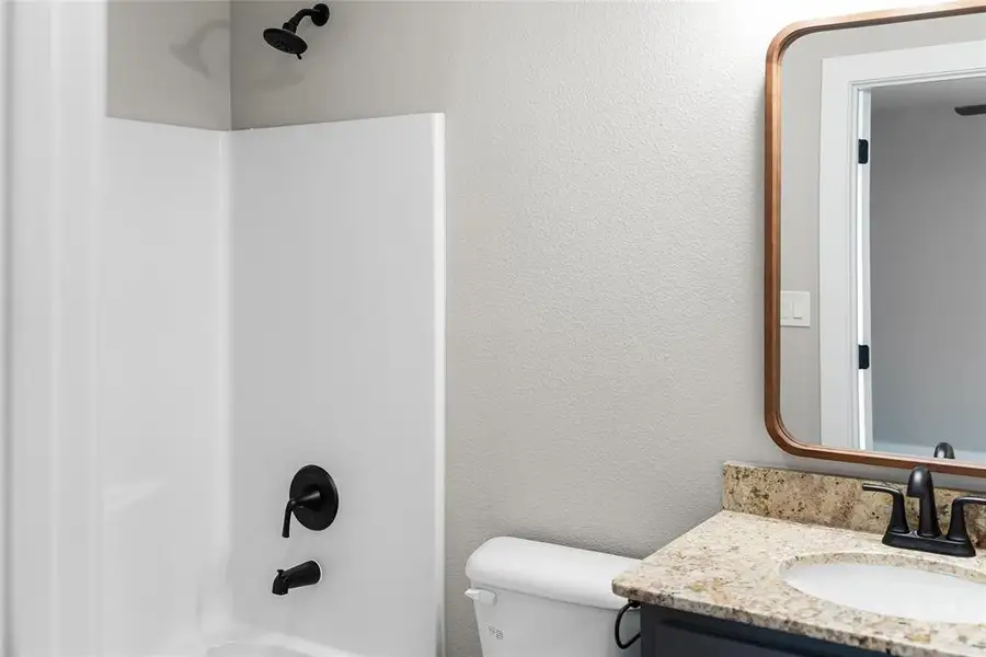 Bathroom featuring toilet, vanity, and washtub / shower combination