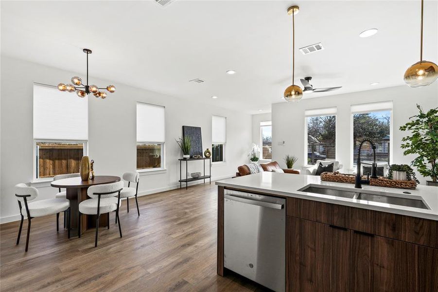 Kitchen featuring dark brown cabinetry, sink, stainless steel dishwasher, dark hardwood / wood-style floors, and ceiling fan with notable chandelier