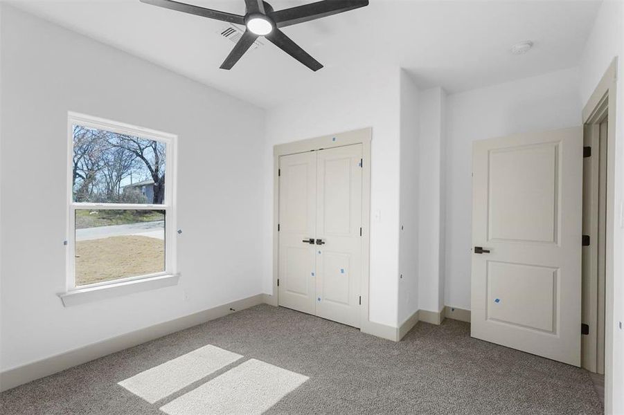 Unfurnished bedroom featuring a closet, light colored carpet, baseboards, and ceiling fan