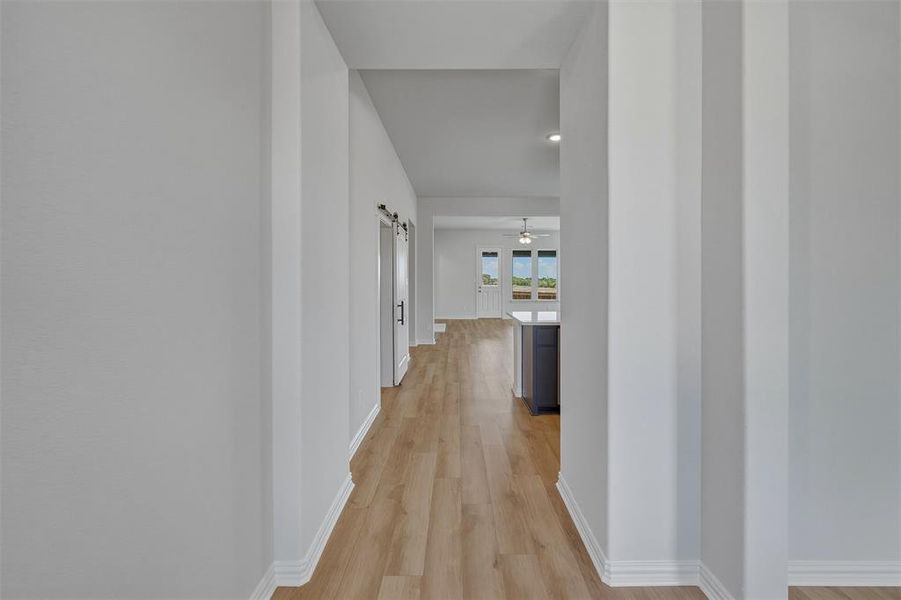 Hallway featuring wood-finish flooring, white baseboards, and light gray walls Hallway featuring wood-finish flooring, white baseboards, and light gray walls