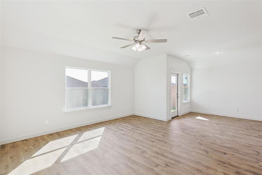 Spare room with ceiling fan, lofted ceiling, and light wood-type flooring