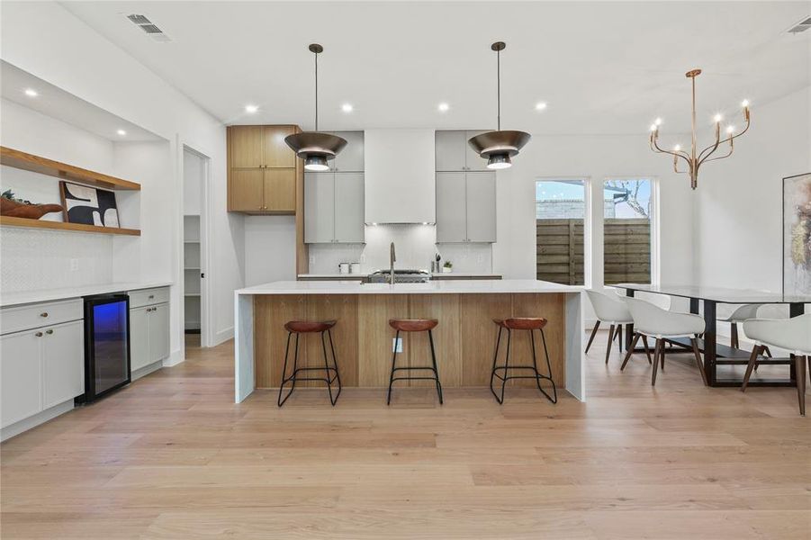 Kitchen with open shelves, decorative light fixtures, modern cabinets, a kitchen bar, and light stone counters