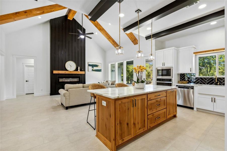 Kitchen with light stone counters, appliances with stainless steel finishes, ceiling fan, and white cabinetry