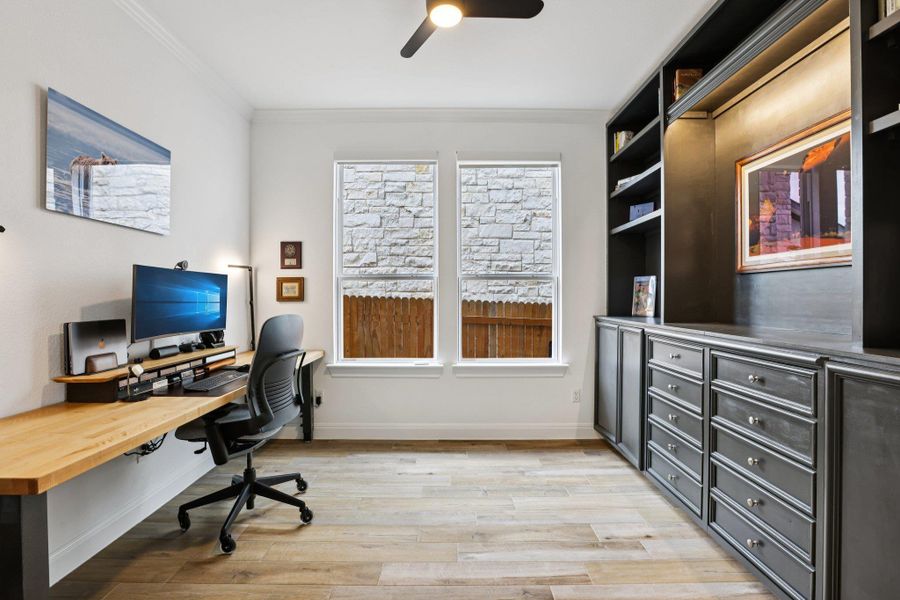 This room features built-in shelving with integrated lighting, wood flooring, and two windows