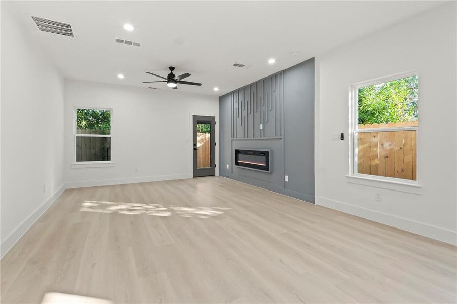 Unfurnished living room with light wood finished floors, recessed lighting, a large fireplace, and a ceiling fan