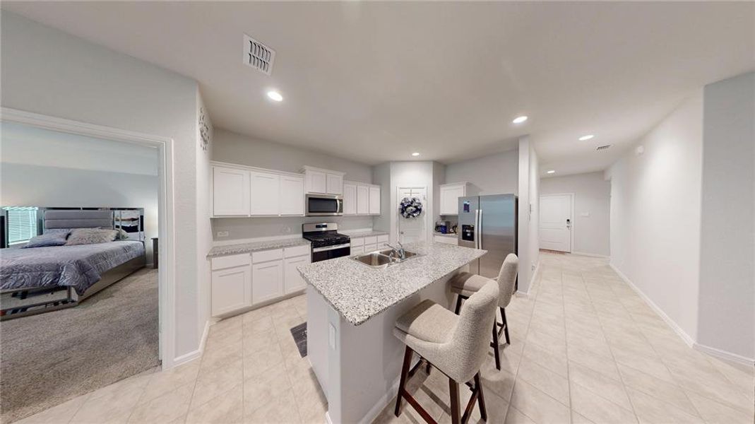 Modern kitchen featuring white cabinetry, light-toned countertops, and a central island with a double basin sink