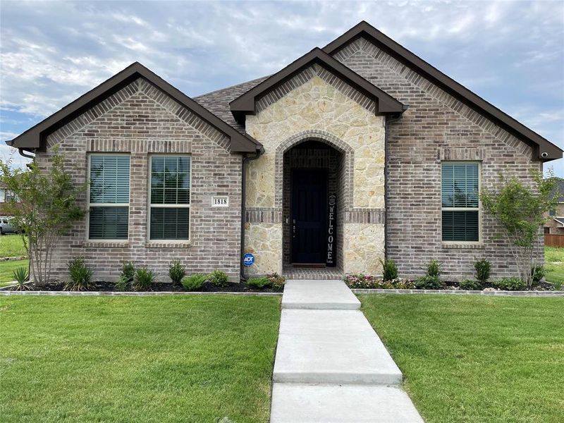 View of front of home featuring a front lawn, stone siding, and brick siding View of front of home featuring a front lawn, stone siding, and brick siding