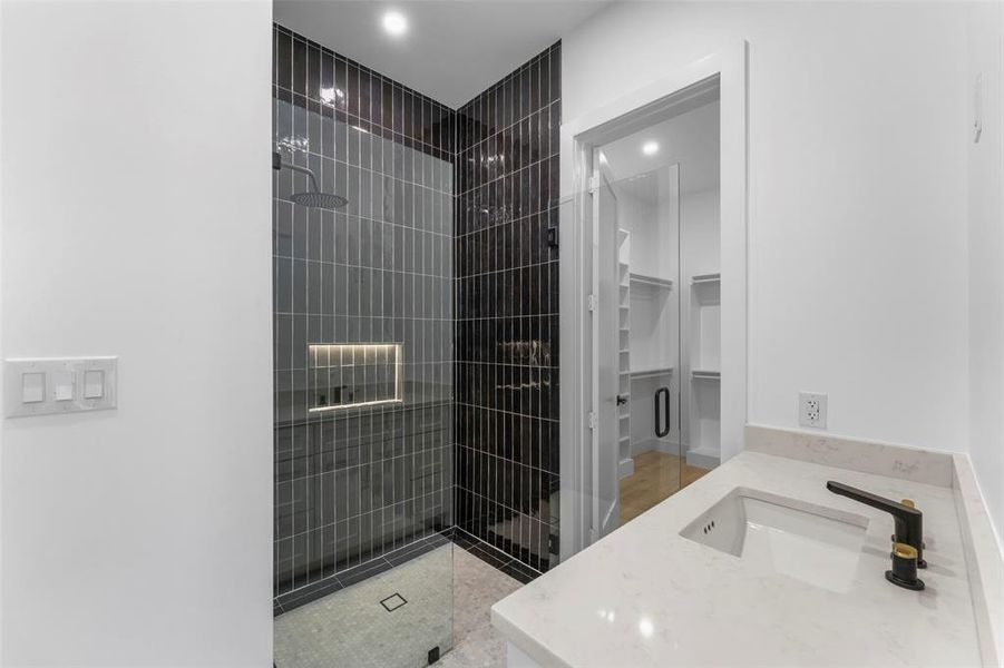 Bathroom with vanity, a walk in closet, and a tile shower