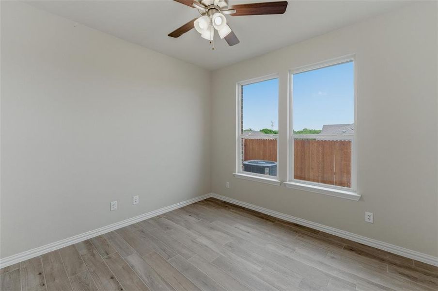 Bright interior room featuring wood-finish flooring, white baseboards, and neutral wall tones