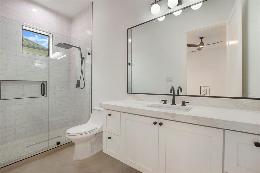 Bathroom with walk in shower, vanity, ceiling fan, tile patterned flooring, and toilet