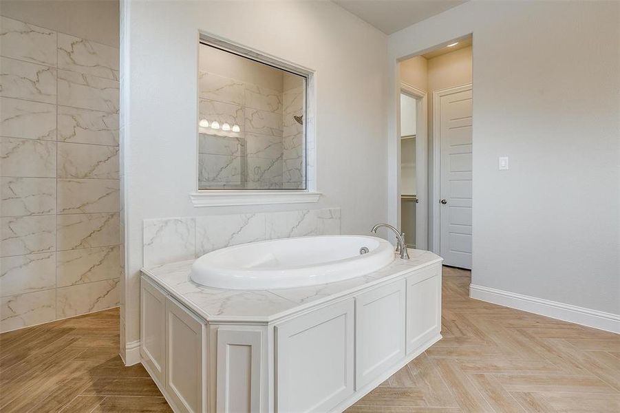 Bathroom with a bathtub and parquet flooring