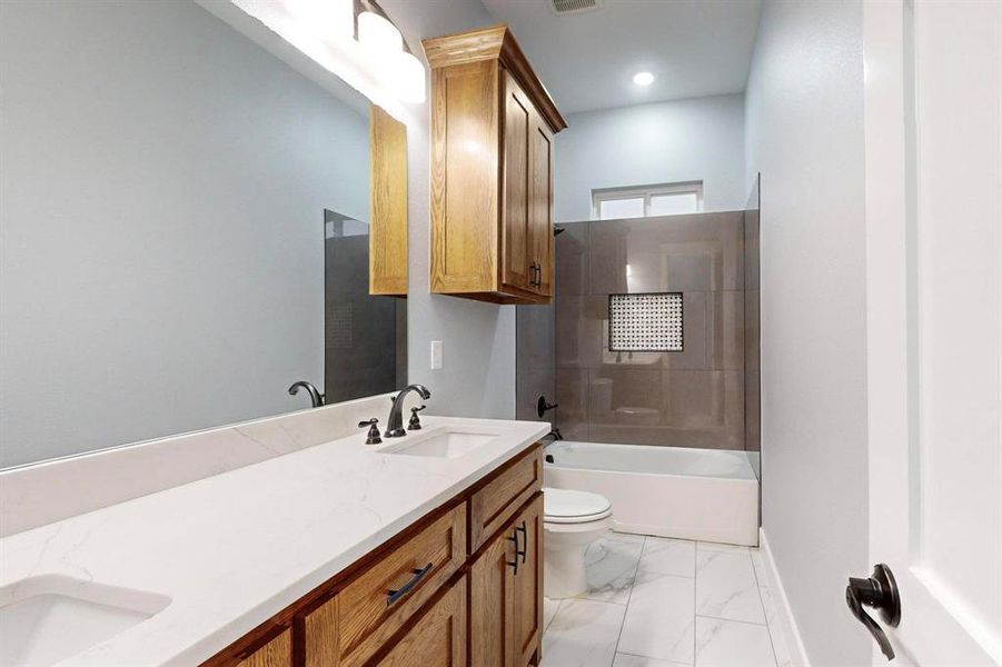 Full bathroom with vanity, toilet, and tiled shower / bath