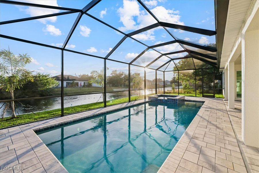 View of pool featuring a sunroom, a lanai, a water view, a pool with connected hot tub, and a patio area