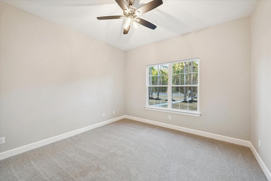 Secondary bedroom with carpeted flooring and lighted ceiling fan.