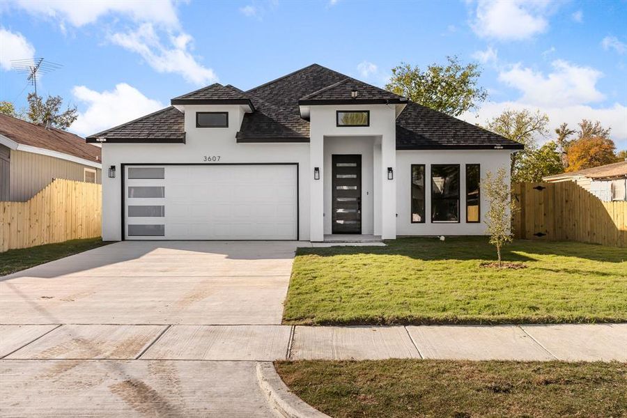 View of front facade featuring a garage and a front lawn