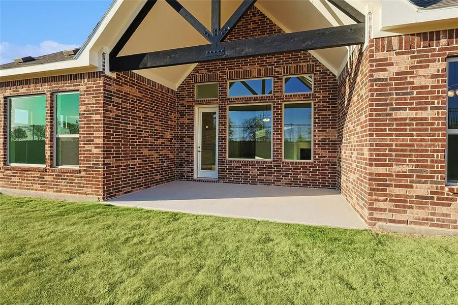 View of exterior entry with a patio, brick siding, and a yard View of exterior entry with a patio, brick siding, and a yard