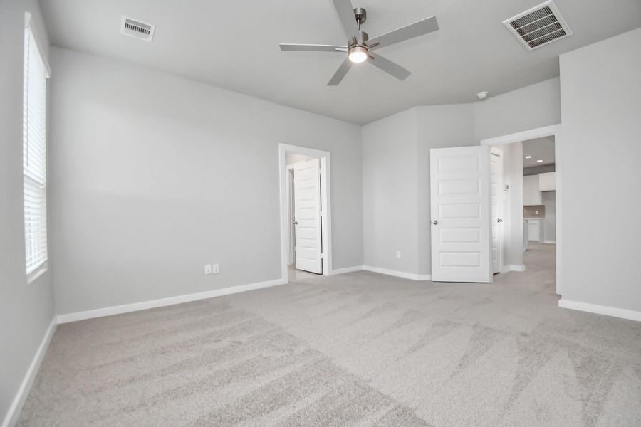 Retreat to the luxurious primary suite, your perfect escape for unwinding after a long day. Located on the first floor, this spacious room features plush carpeting, calming paint tones, high ceilings, and large windows with privacy blinds. Sample photo of completed home with similar floor plan. Actual colors and selections may vary.