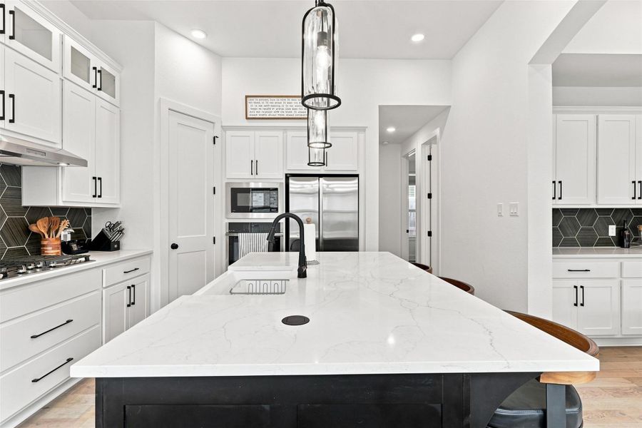 Gleaming stone countertops and sleek modern cabinetry anchor this beautifully designed culinary space.