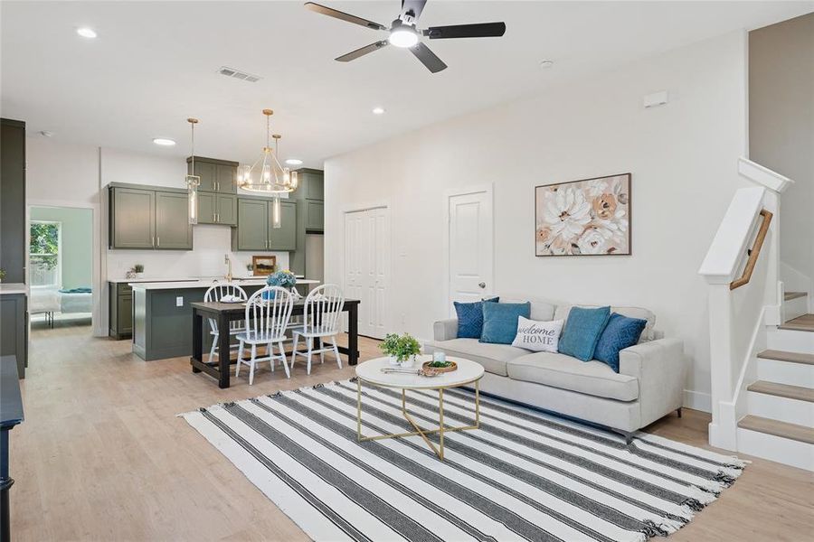Living room featuring light wood-style flooring, recessed lighting, a chandelier, stairway, and ceiling fan