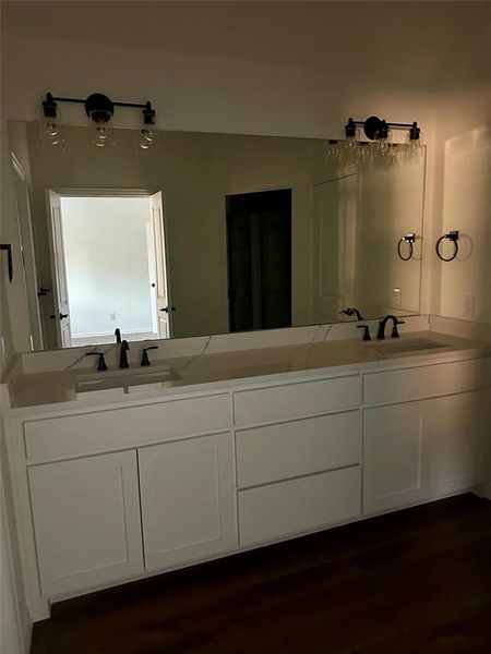 Full bathroom with double vanity and dark wood finished floors