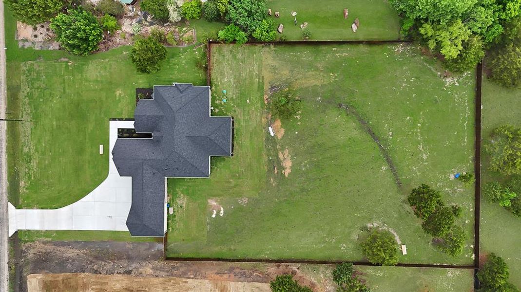 Expansive property featuring a dark roof, a light-colored driveway, and a large lawn area