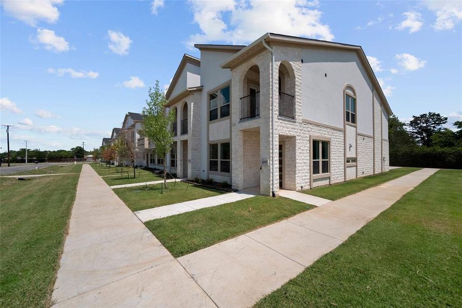 View of property exterior with a lawn and a balcony