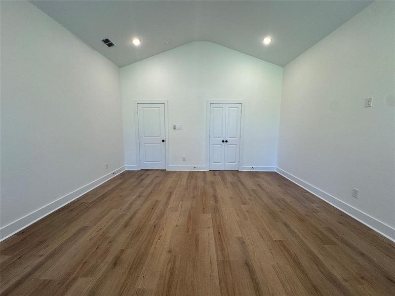 Empty room featuring hardwood / wood-style floors and vaulted ceiling