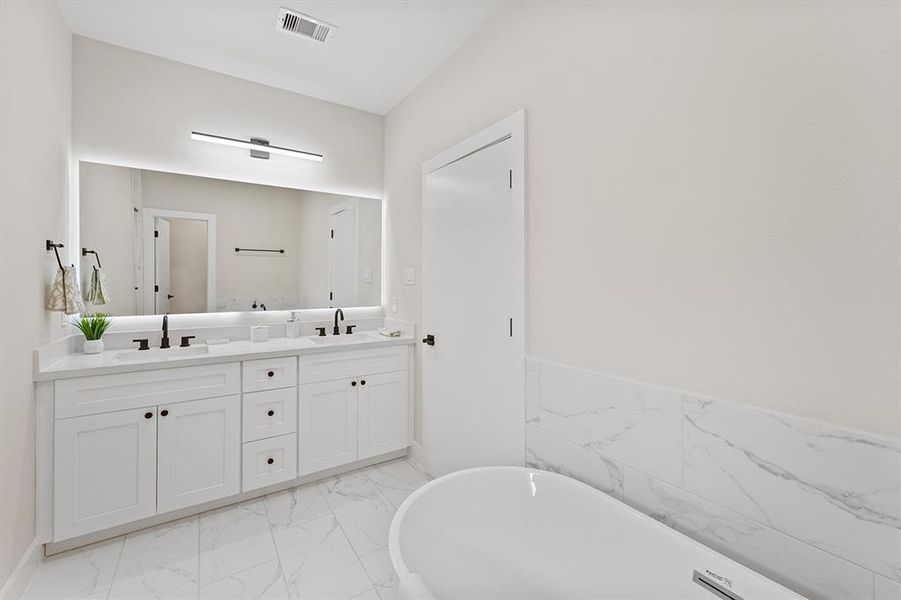 A modern bathroom with a double vanity, large mirror, marble countertop, and a freestanding bathtub. Clean, white, and well-lit.