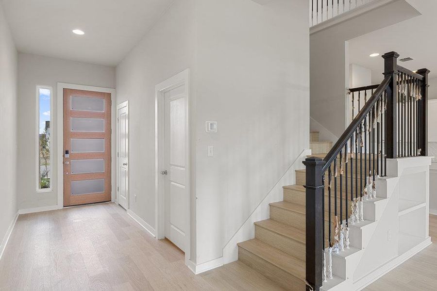 Foyer with recessed lighting, light wood finished floors, and stairway