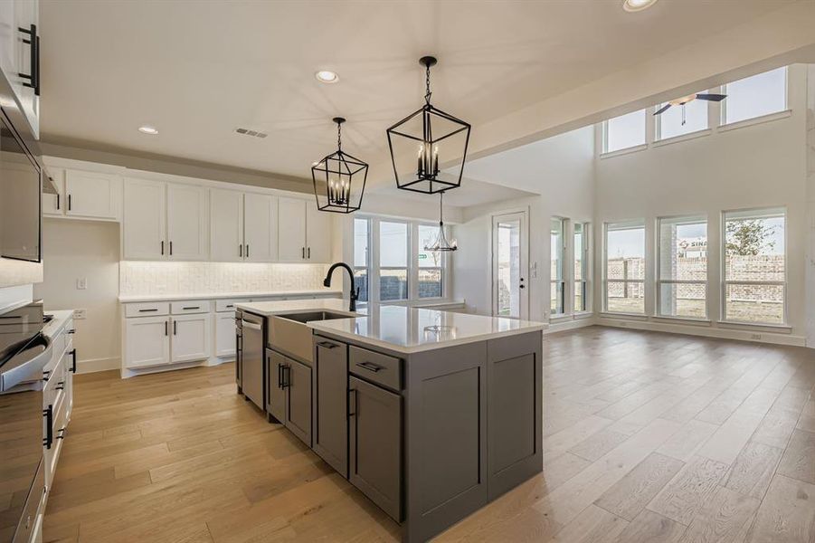 Kitchen with white cabinetry, an island with sink, decorative backsplash, recessed lighting, and light wood-type flooring