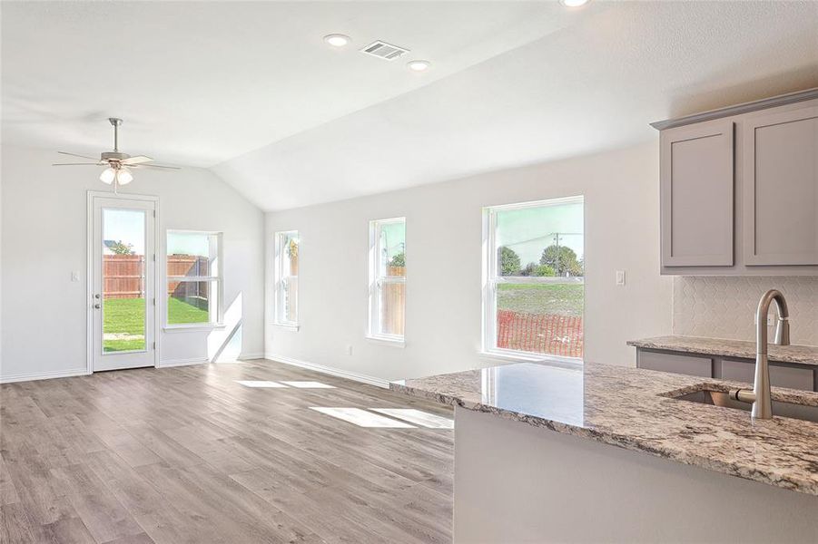 Living room featuring a healthy amount of sunlight, light hardwood / wood-style floors, vaulted ceiling, and sink