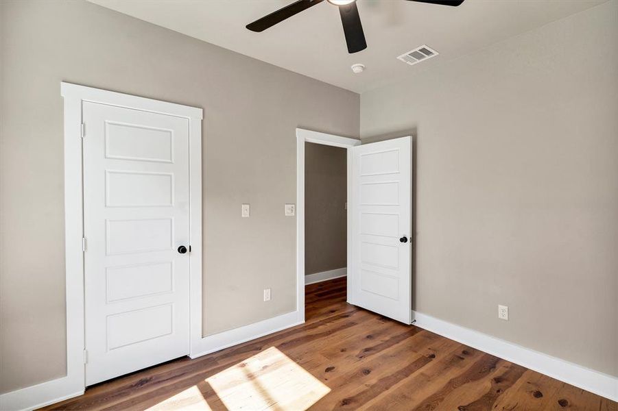 Unfurnished bedroom with wood finished floors and a ceiling fan Unfurnished bedroom with wood finished floors and a ceiling fan