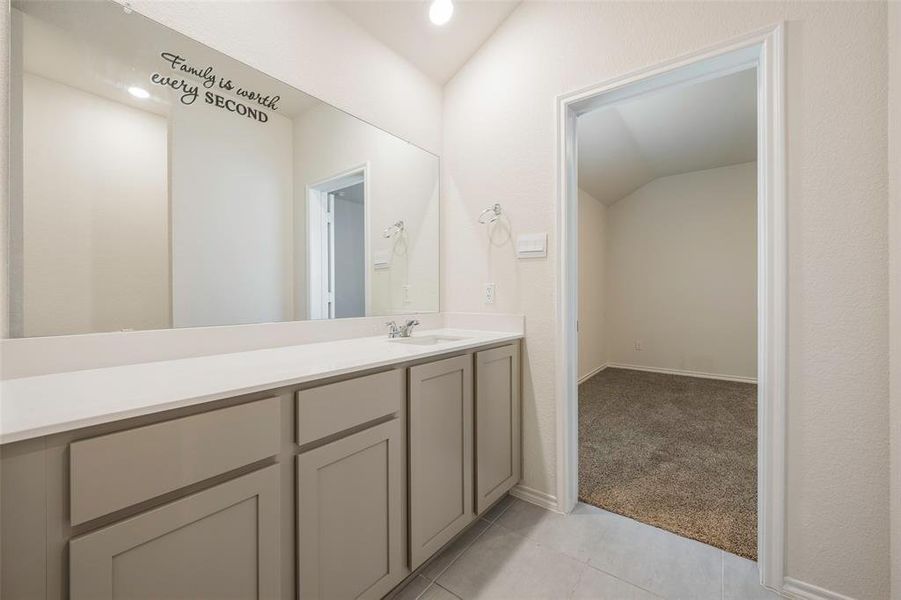 Bathroom with vanity, tile patterned flooring, and vaulted ceiling