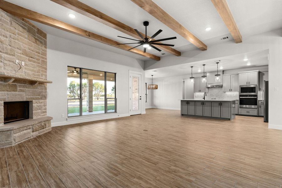Unfurnished living room featuring a ceiling fan, a fireplace, light wood-style flooring, recessed lighting, and beamed ceiling Unfurnished living room featuring a ceiling fan, a fireplace, light wood-style flooring, recessed lighting, and beamed ceiling