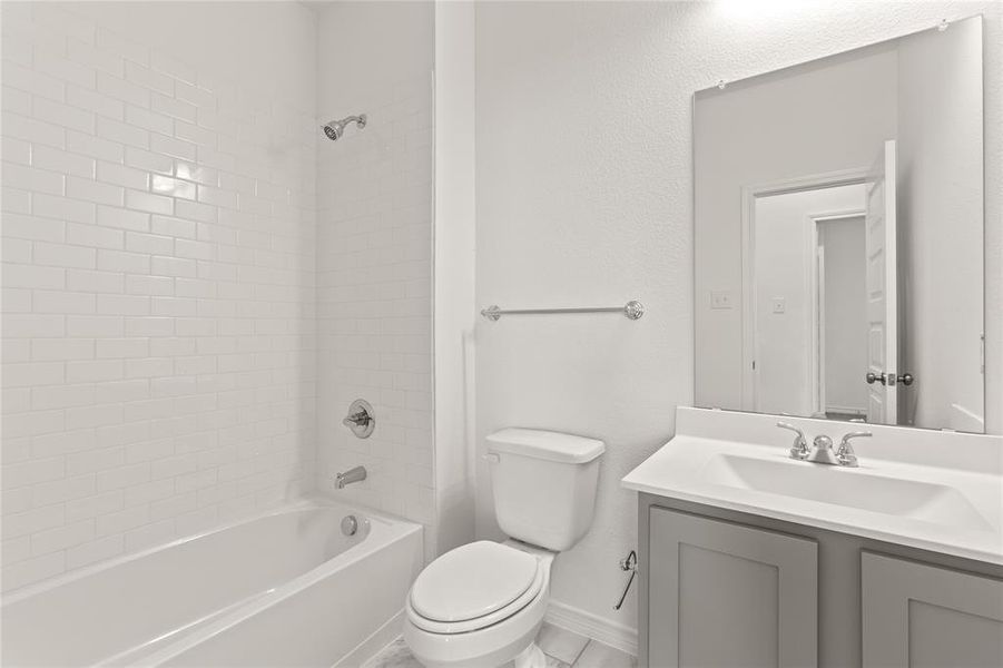 Full bathroom with tiled shower / bath combo, toilet, and vanity