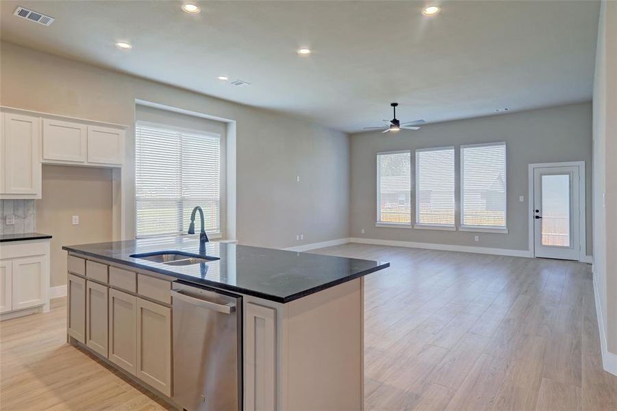 Kitchen with light wood-style flooring, stainless steel dishwasher, recessed lighting, open floor plan, and a ceiling fan Kitchen with light wood-style flooring, stainless steel dishwasher, recessed lighting, open floor plan, and a ceiling fan