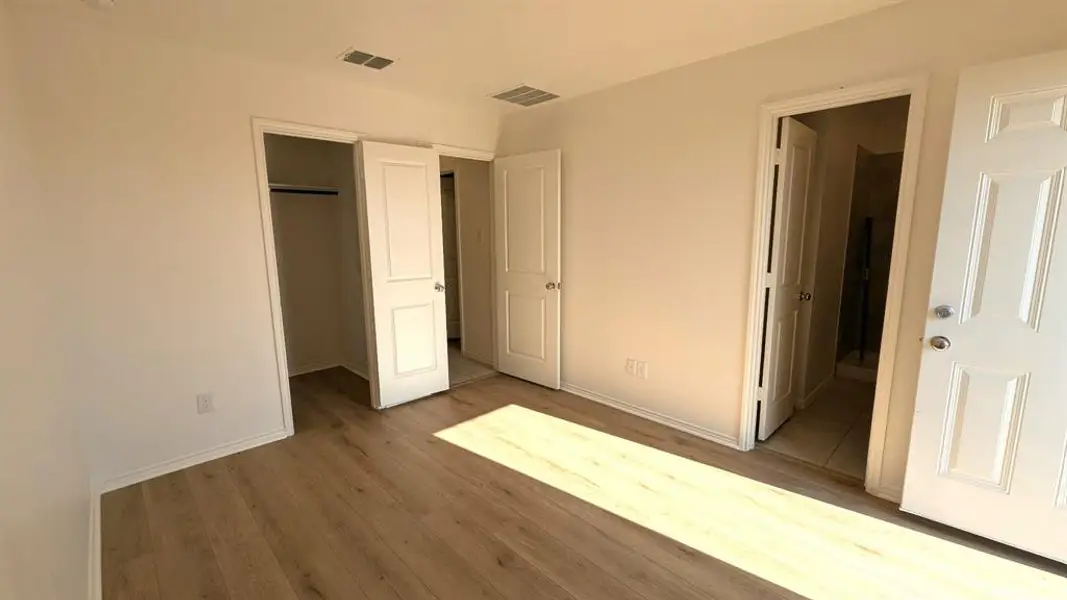 Unfurnished bedroom featuring wood finished floors and a walk-in closet Unfurnished bedroom featuring wood finished floors and a walk-in closet