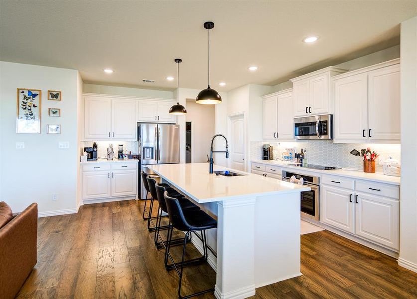 Kitchen with white cabinets, dark wood-type flooring, and a kitchen breakfast bar